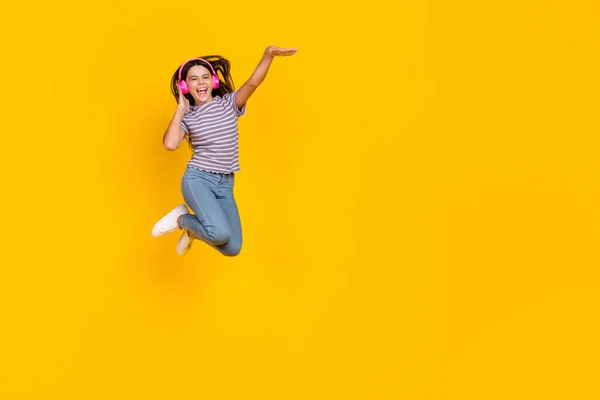 Foto de tamaño completo de señora joven saltar escuchar auriculares de radio meloman aislado sobre fondo de color amarillo —  Fotos de Stock