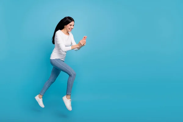 Teljes hosszúságú testméret kilátás vonzó vidám aktív lány jumping segítségével eszköz blog elszigetelt élénk kék színű háttér — Stock Fotó