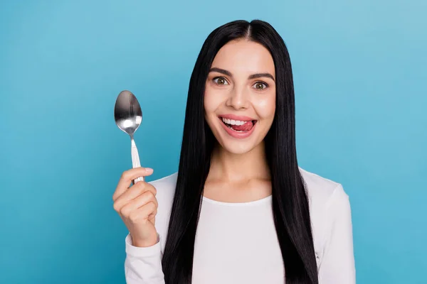 Foto de milenar bonito morena senhora segurar colher lamber usar pano branco isolado no fundo de cor azul — Fotografia de Stock