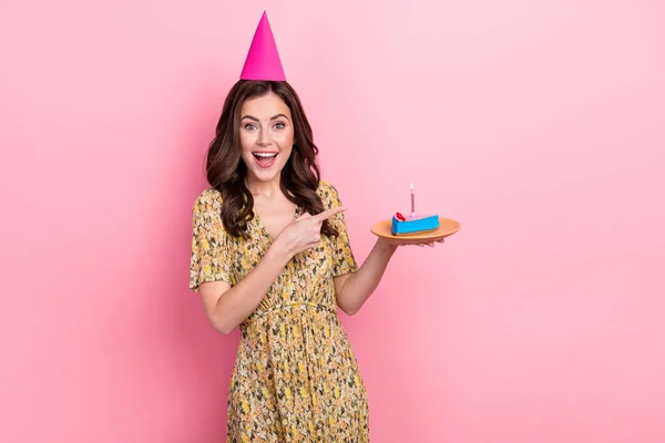 Portret van opgewonden positief meisje geven vinger cake look camera geïsoleerd op roze kleur achtergrond — Stockfoto