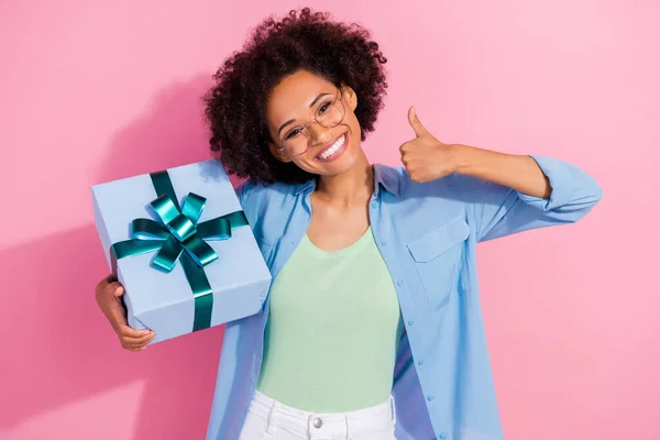 Foto de confiança positiva agradável senhora segurar presente giftbox levantar polegar aprovar desgaste camisa jeans isolado cor rosa fundo — Fotografia de Stock