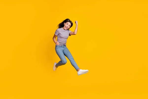 Foto de tamaño completo de la joven se regocijan éxito puños manos triunfo salto aislado sobre fondo de color amarillo —  Fotos de Stock
