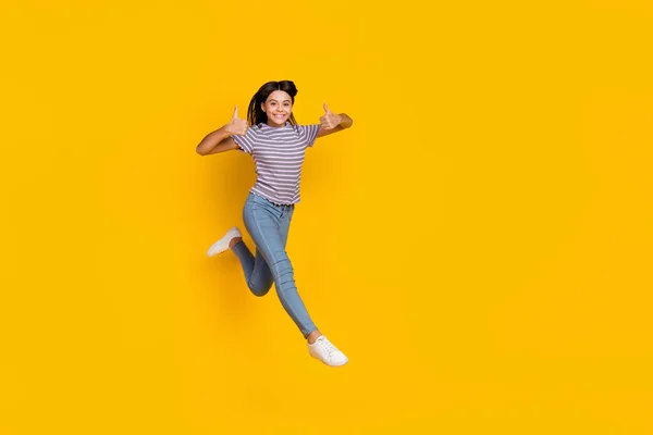 Foto de corpo inteiro de jovem salto mostra polegares-up aprovar anúncios selecionados bom isolado sobre fundo de cor amarela — Fotografia de Stock