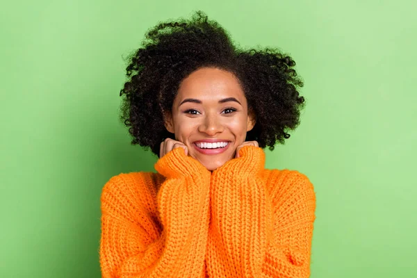 Etkilenmiş genç kadın saçlarının fotoğrafı yeşil arka planda izole edilmiş turuncu kazak giyer. — Stok fotoğraf