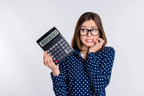 Portret atrakcyjnej nerwowej dziewczyny trzymającej kalkulator ujemne saldo pieniędzy izolowane nad szarym pastelowym tle koloru — Zdjęcie stockowe