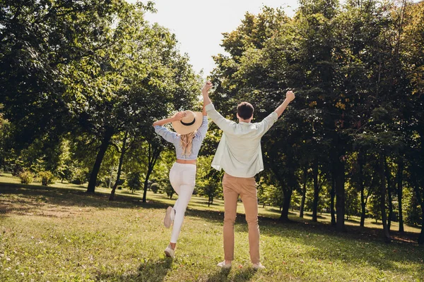 Achterzijde achter de volledige lengte lichaam uitzicht van twee aantrekkelijke schattige paar levenspartners echtgenoten genieten springen plezier buiten — Stockfoto