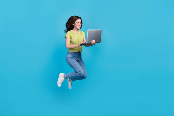 Πλήρης φωτογραφία του σώματος του SEO νεαρή μελαχρινή κυρία άλμα τύπου laptop φορούν t-shirt τζιν παπούτσια απομονώνονται σε μπλε φόντο — Φωτογραφία Αρχείου