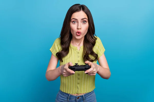 Foto van onder de indruk millennial brunette dame playstation dragen groene t-shirt geïsoleerd op blauwe achtergrond — Stockfoto