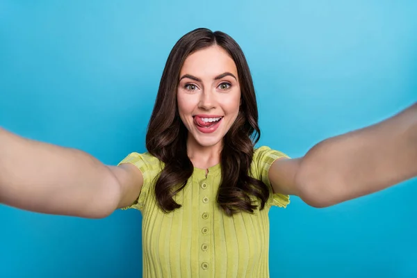 Bild av cool ung brunett lockigt frisyr gör selfie slicka läpp bära grön topp isolerad på blå färg bakgrund — Stockfoto