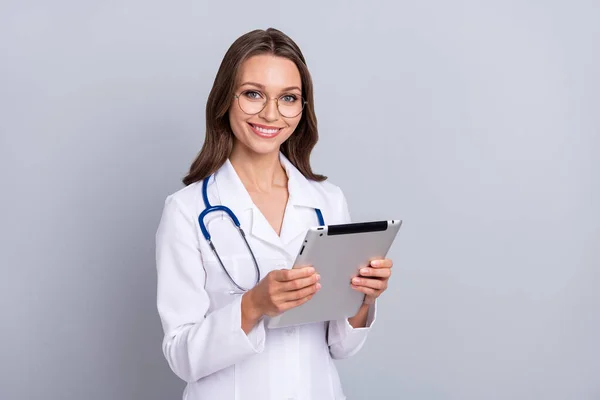 Fénykép a vidám nő orvos használja tabletta konzultáció kopás fehér kabátot elszigetelt szürke színű háttér — Stock Fotó