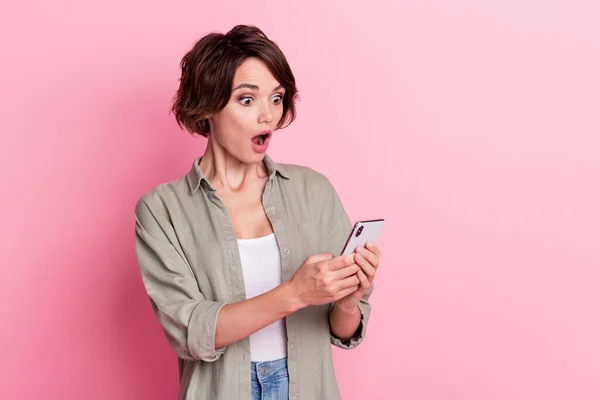 Foto van onder de indruk mooie dame open mond staren telefoon onverwachte dragen groen shirt geïsoleerd op roze kleur achtergrond — Stockfoto