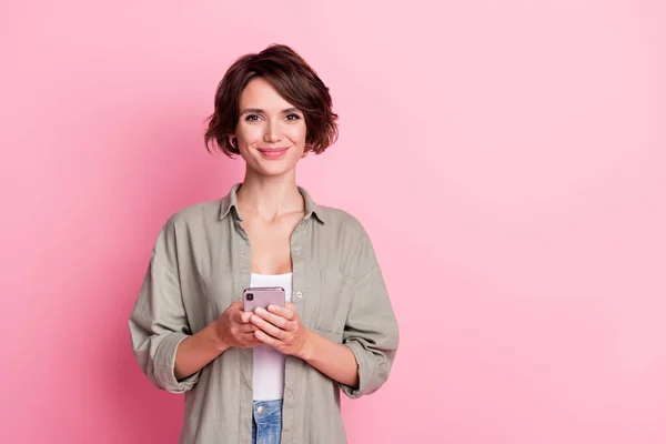 Foto di affascinante signora tenere telefono sguardo fotocamera usura camicia kaki isolato su sfondo di colore rosa — Foto Stock