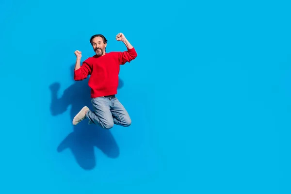 Pełny rozmiar zdjęcie funky radowany mężczyzna skoki podnieść pięści w zwycięstwie świętować wsparcie wentylatora izolowane na niebieskim tle kolor — Zdjęcie stockowe