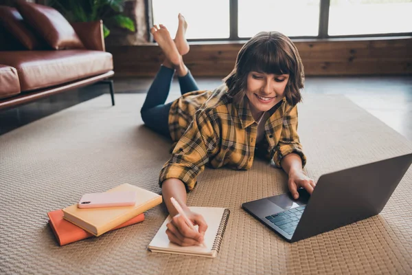 Photo of smart concentrated woman lying floor browsing on laptop make notes homework studying at home — Stock Photo, Image