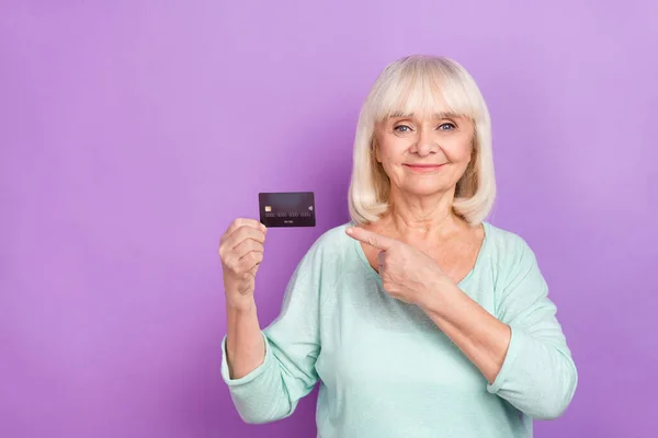 Foto di bella positivo vecchia signora direttamente indice carta di debito usura camicia turchese isolato colore viola sfondo — Foto Stock