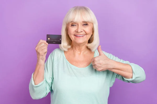 Foto de senhora confiante segurar cartão de débito levantar polegar positivo feedback desgaste camisa azul isolado cor roxa fundo — Fotografia de Stock