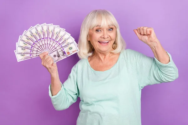 Fénykép vidám megdöbbent idős hölgy hold készpénz fan raise ököl öröm viselni kék ing elszigetelt lila szín háttér — Stock Fotó