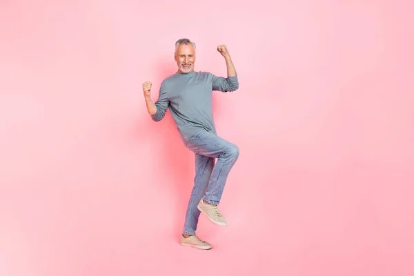 Foto van gelukkige charmante man gepensioneerde gekleed grijs shirt lopen rijzende vuisten geïsoleerde roze kleur achtergrond — Stockfoto