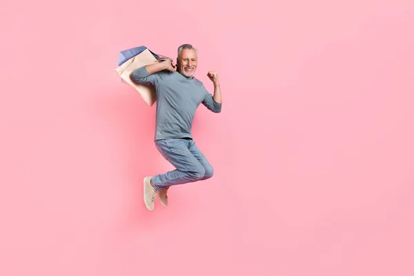 Photo of pretty lucky retired man wear grey shirt jumping rising fist shoppers empty space isolated pink color background — Stock Photo, Image