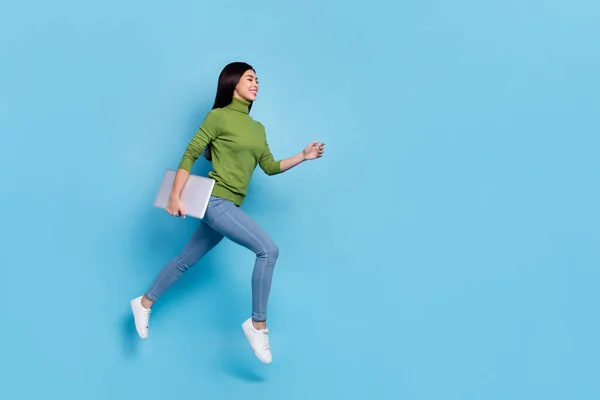 Full body foto van funky millennial brunette dame lopen met laptop slijtage jumper jeans schoenen geïsoleerd op blauwe achtergrond — Stockfoto
