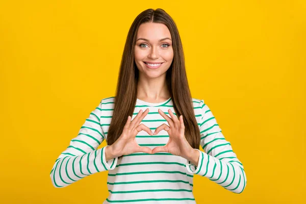 Foto di sognante donna lucida vestita camicia a righe che mostra le mani cuore isolato colore giallo sfondo — Foto Stock