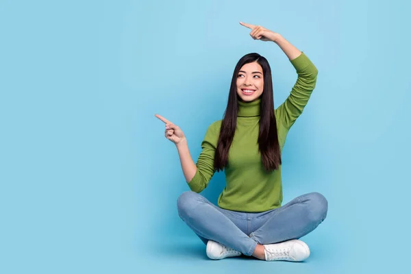 Retrato de chica alegre atractiva sentada pose de loto demostrando espacio de copia aislado sobre fondo de color azul brillante —  Fotos de Stock