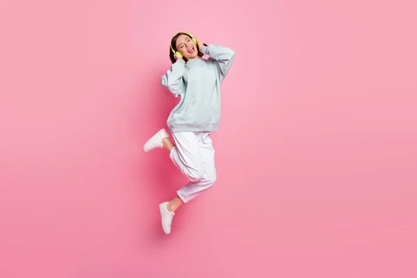 Ganzkörper-Foto von Hurra Bob Frisur junge Dame springen tragen Kopfhörer Kapuzenpullover Hose Turnschuhe isoliert auf rosa Hintergrund — Stockfoto