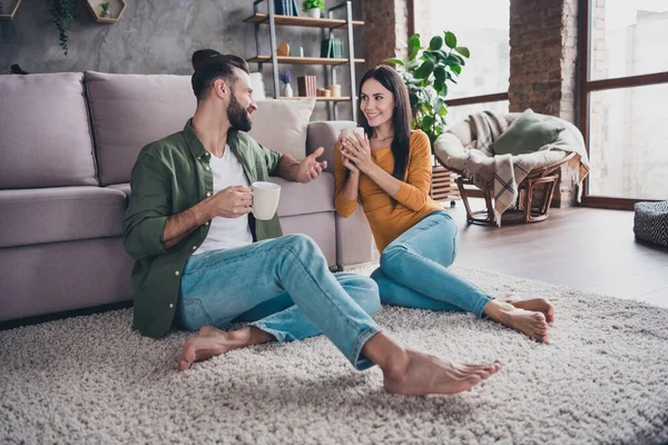 Portrait of attractive cute cheerful couple sitting on floor carpet communicating spending day drinking cacao at home house flat indoors — Stock Photo, Image
