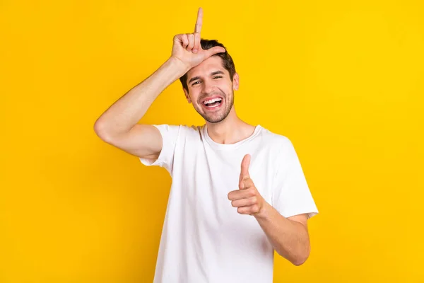 Foto de homem tolo louco funky fazer sinal de chifre dedo direto que você usa t-shirt branca isolado fundo cor amarela — Fotografia de Stock