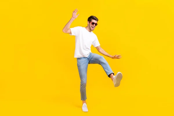 Foto corpo pieno di fresco giovane brunetta ragazzo danza indossare occhiali t-shirt jeans calzature isolate su sfondo giallo — Foto Stock