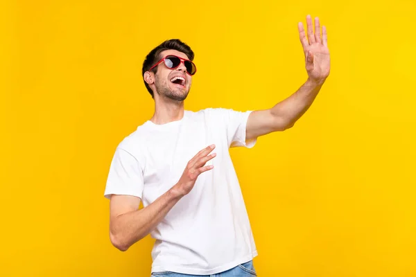 Foto de impressionado millennial morena cara dança onda desgaste óculos t-shirt isolado no fundo de cor amarela — Fotografia de Stock