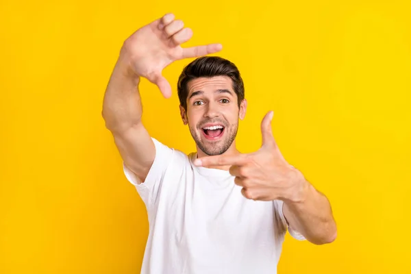 Photo of impressed young brunet guy do photo wear white t-shirt isolated on yellow color background — Foto Stock