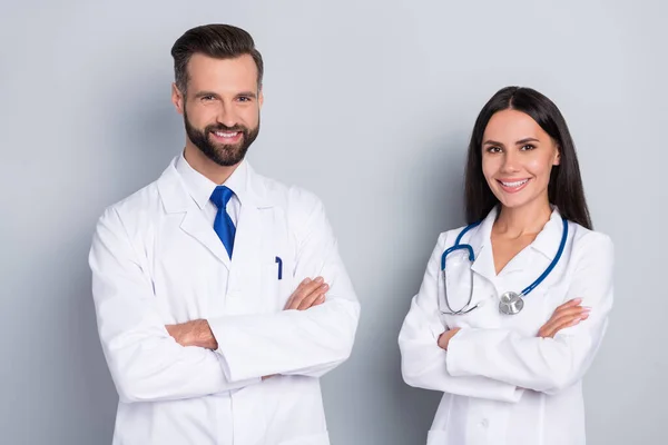 Retrato de dos médicos cirujanos inteligentes alegres cruzaron las manos aisladas sobre fondo de color gris — Foto de Stock