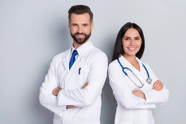 Foto de dos médicos profesionales positivos brazos plegados mirar cámara aislada sobre fondo de color gris — Foto de Stock