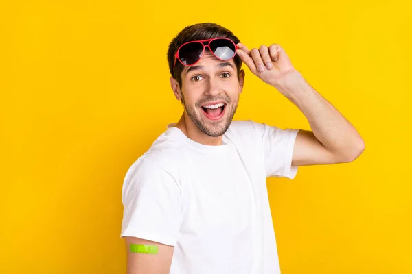 Foto di impressionato giovane ragazzo brunetta ha fatto vaccinazione indossare occhiali t-shirt isolata su sfondo di colore giallo — Foto Stock