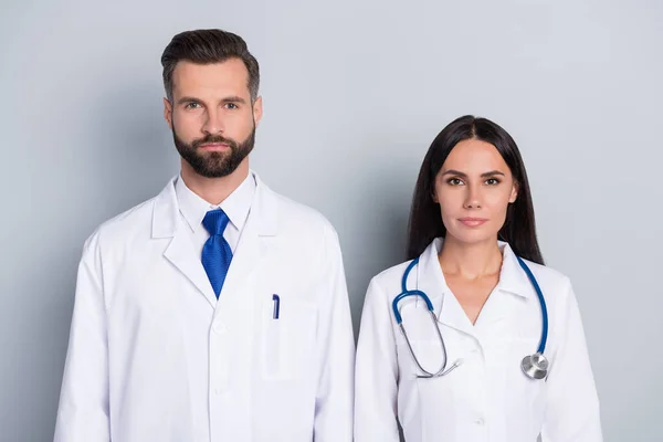 照片上，两位医生身穿白衣，很自信，准备参考你孤立的灰色背景 — 图库照片