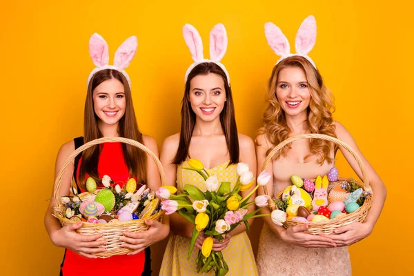 Tři legrační sestry dámy drží velikonoční dárky přišla rodina shromažďování tradiční setkání nosit nadýchané uši izolované žluté pozadí — Stock fotografie