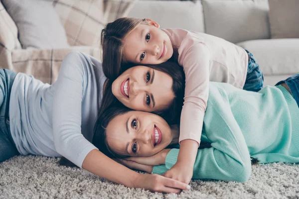 Портрет привлекательной сладкой веселой семьи, лежащей на полу и наслаждающейся домашним уютом, весело проводя время дома в помещении — стоковое фото