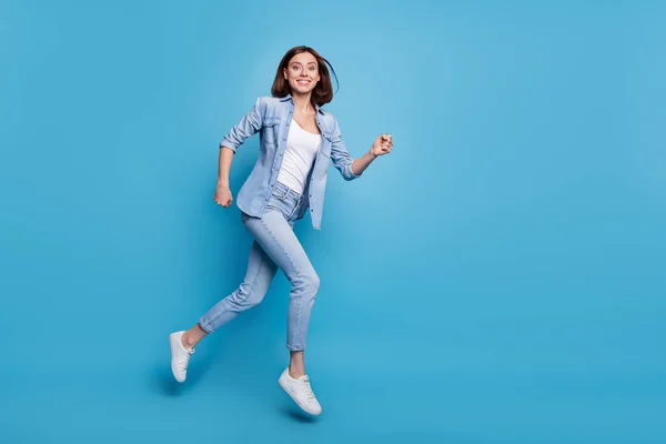 Foto de adorable linda dama vestida camisa de mezclilla corriendo rápido saltando alto aislado color azul fondo —  Fotos de Stock