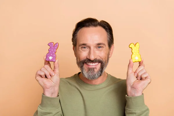 Porträt von attraktiven fröhlichen lustigen Mann hält in der Hand süße Hasen Ostern Zeit isoliert über beige Pastellfarbe Hintergrund — Stockfoto