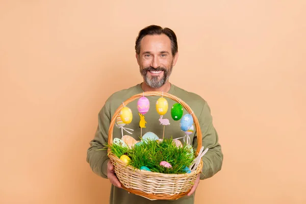 Porträt von attraktiven fröhlichen Mann hält in den Händen festliche Dekor Korb Ostern Zeit isoliert über beige Pastellfarbe Hintergrund — Stockfoto