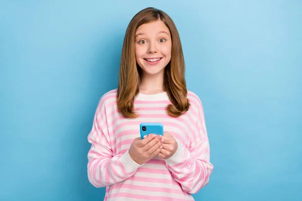 Portrait de fille mignonne positive tenir téléphone recevoir notification app regarder caméra isolé sur fond de couleur bleue — Photo