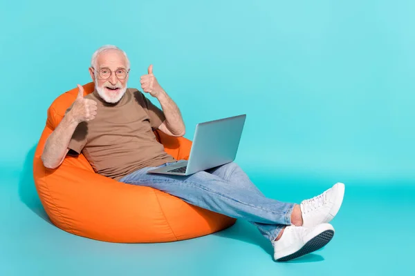 Portret przystojnego modnego wesołego siwego mężczyzny używającego laptopa pokazującego odizolowany kciuk na jasnoniebieskim tle — Zdjęcie stockowe