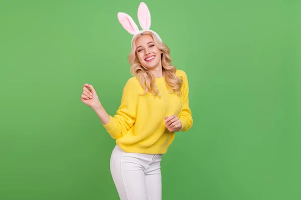 Zdjęcie słodkie młoda blondynka pani taniec nosić uszy żółty pullover spodnie izolowane na zielonym tle kolor — Zdjęcie stockowe