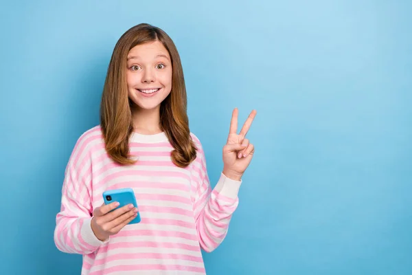 Pozitif çekici liseli kızın portresi telefon tut v-işaretini mavi arka planda izole et — Stok fotoğraf