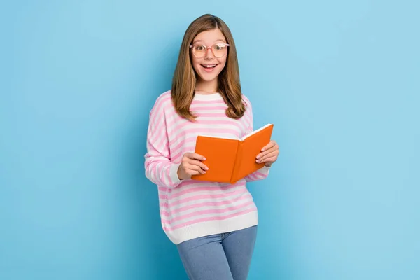 Portrét pozitivní veselá dívka držet knihu zářící úsměv vzhled kamery izolované na modrém pozadí — Stock fotografie