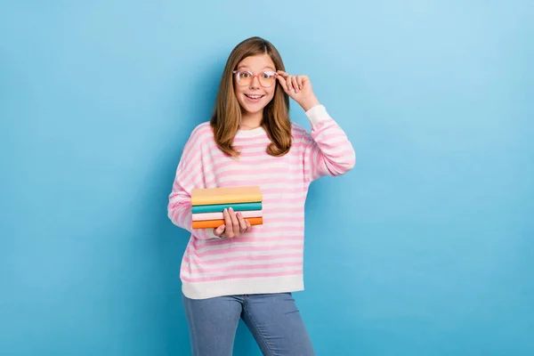 Portrét přátelské spokojené dívky držet knihu ruka dotek brýle zubatý úsměv izolované na modrém pozadí — Stock fotografie