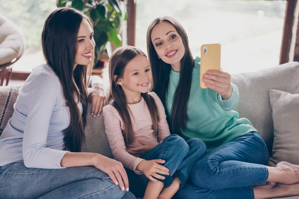 Foto de tres encantadora chica disparar foto selfie hablar video llamada teléfono celular sentado diván plana en el interior —  Fotos de Stock
