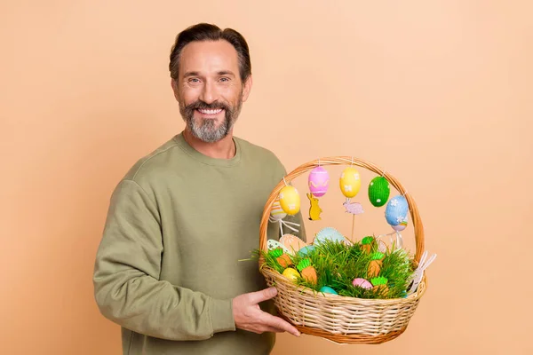 Porträt eines attraktiven, fröhlichen Mannes mit festlichem Korb in der Hand, der seinen Traum isoliert über beige pastellfarbenem Hintergrund vorbereitet — Stockfoto