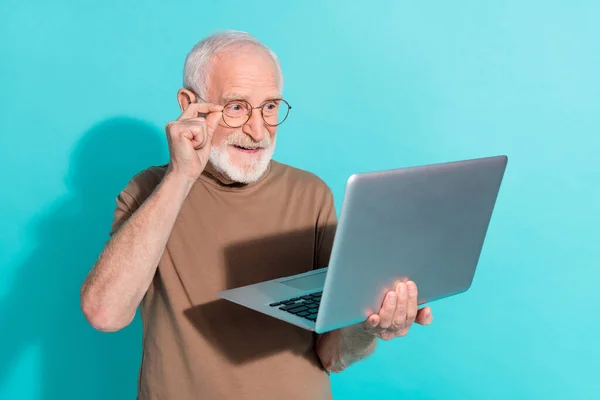 Portrét atraktivní zručný šedovlasý muž pomocí notebooku objednávka eshop izolované přes jasně modré barvy pozadí — Stock fotografie